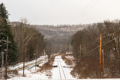 Train tracks in snow covered woods in Warren County, Pennsylvania, USA on an overcast winter day