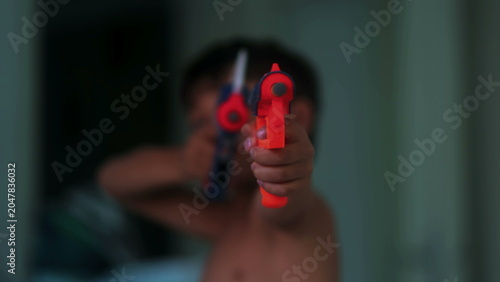 Foto Young boy aiming colorful toy blasters toward camera during imaginative indoor p