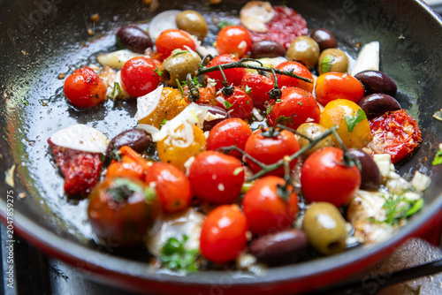 Tableau sur toile Colorful cherry tomatoes and olives sauteed in a pan with herbs.