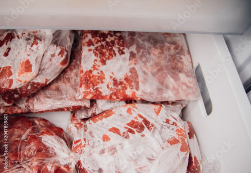 Various frozen beef cuts packed in bags inside the freezer. The concept of food preservation.