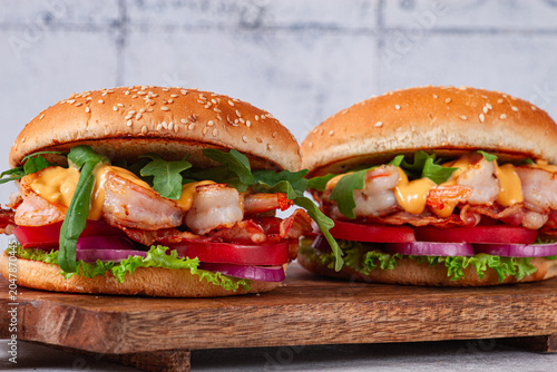 Fotografie Shrimp burgers with fresh ingredients are served on a wooden board in a bright k