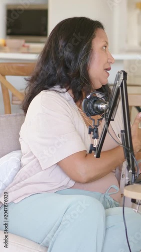 Vertical video: Hearing cue, host tapping tablet, using mic on sofa, pausing then looking shocked