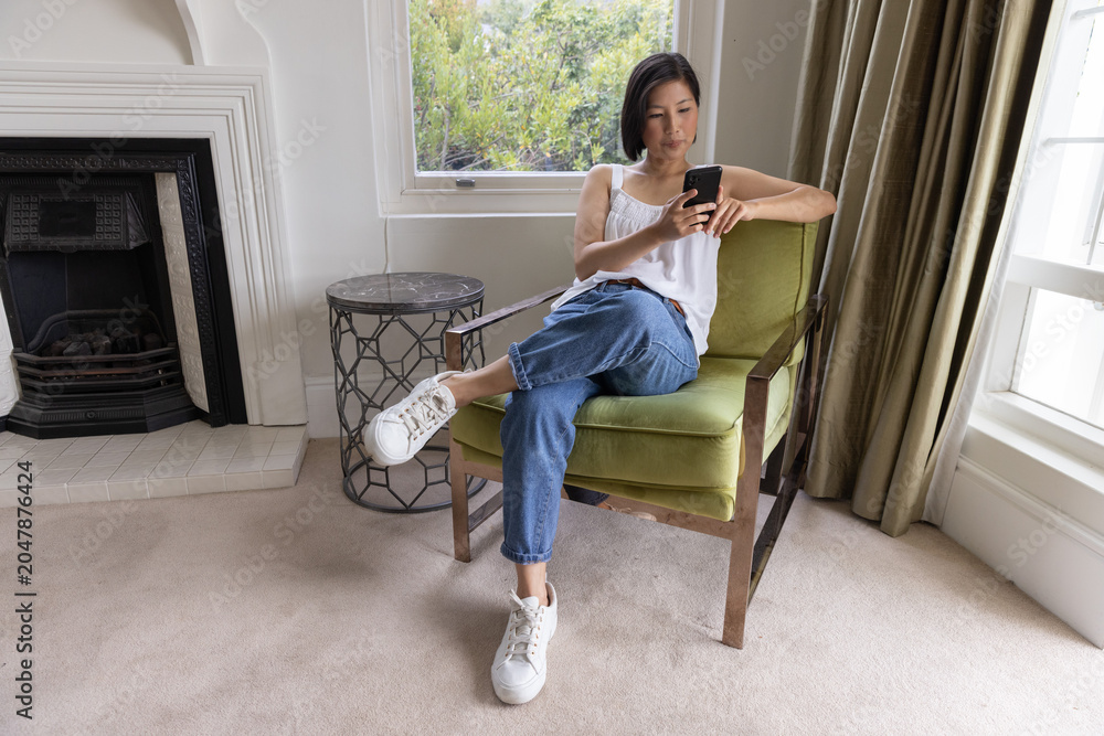Obraz premium Green upholstered armchair is sitting near sash window, with marble side table and fireplace
