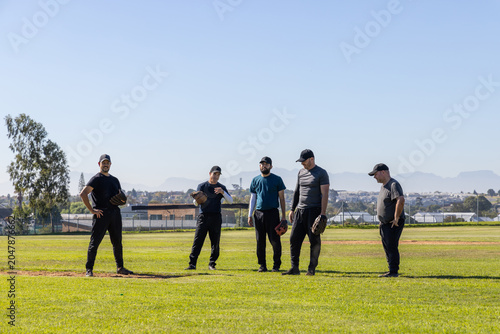 Fotografie Diverse male teammates practicing on baseball infield at suburban park holding g