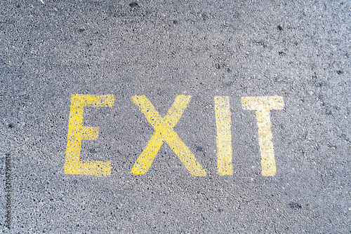 Photography Yellow EXIT text painted on gray asphalt road surface closeup top view