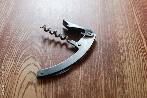 Stainless steel waiter's corkscrew wine bottle opener on a wooden table.