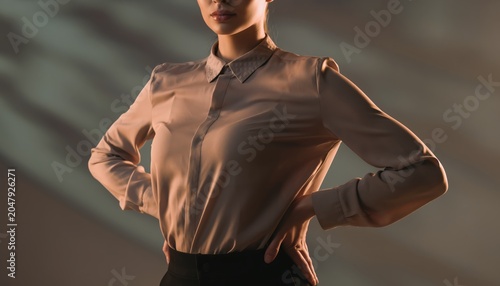 Confident Woman Standing with Hands on Hips in Dramatic Lighting.