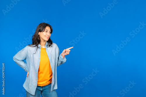 Tableau sur toile Young woman smiling pointing finger right copy space