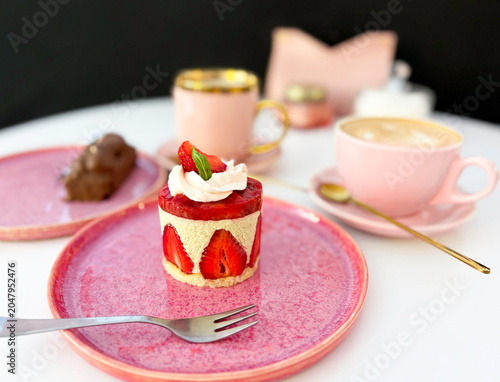 Gourmet strawberry Fraisier cake on pink ceramic plate with coffee cup background. High quality photo