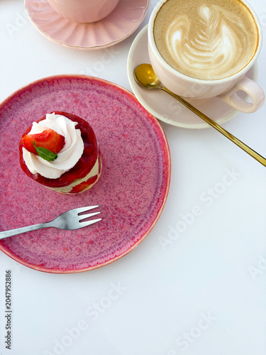 Top view of strawberry mousse cake on pink plate with coffee latte art cup. High quality photo