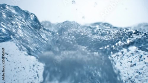 Close-up of Water Pouring with Bubbles and Splashes, Capturing Fluid Motion Against a White Background