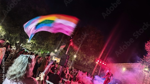 Senior woman waving LGBTQ+ rainbow flag during Pride celebration in rural Mallorca, Spain