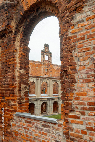 Quadro su tela View through arched brick ruin to historic redbrick courtyard and arcade