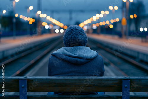 Person Sitting Alone on Station Bench at Evening Platform Glow
