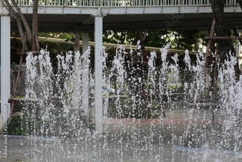 Billede på lærred Refreshing water jets create a dynamic curtain of droplets in an urban park sett
