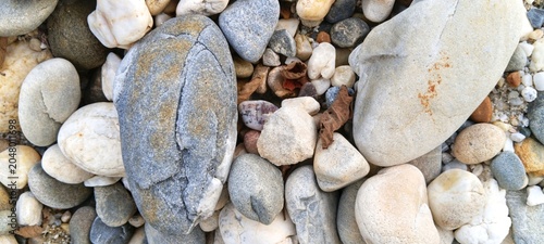 Fotografija Rich dark obsidian-colored river rocks gleaming with water droplets, providing a