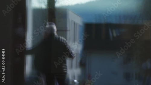 Blurred Reflection of Senior Person Walking in Urban Environment