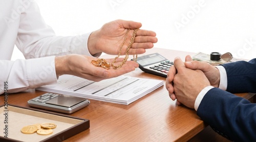 Jeweler showing precious gold chain to a client during a jewelry appraisal or purchase transaction at a store