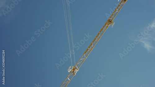 Tower Crane Lifting Concrete Bucket Against Blue Sky