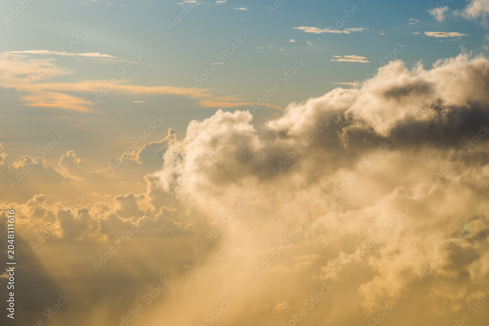 Fototapeta premium Thick cumulus cloud edge blocking the setting sun and creating distinct golden light rays shining down through the evening sky.