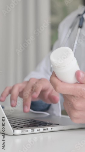 Close up of Doctor Searching on Laptop while Holding Medicine, Vertical Video