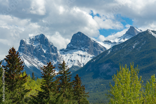 Stunning summertime views in Canada along the Bow River in the town of Canmore with stunning, snow capped peaks in small tourist town. 