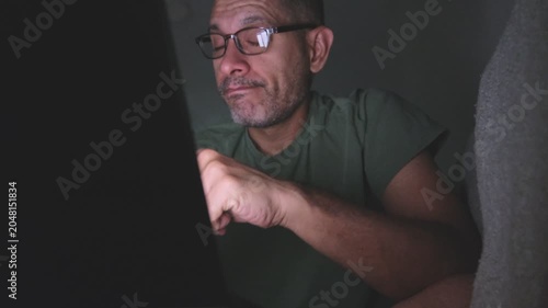 Mature man with glasses working late on laptop at night