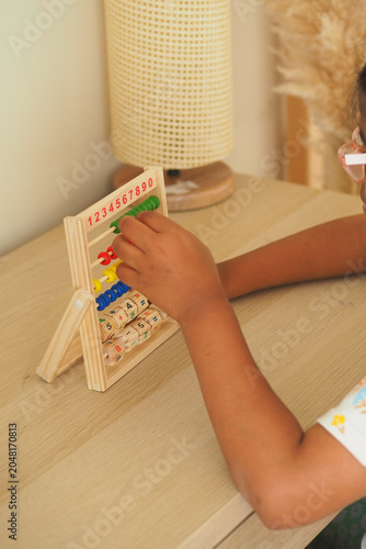 Bild auf Leinwand Child explores numbers using a wooden abacus tool