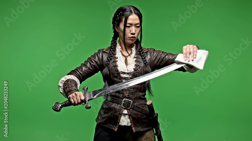 Skilled Warrior Cleaning Sword Against Green Screen Background in Action-Fantasy Scene for Motion and Visual Effects Production