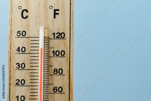 Wooden thermometer indicating hot temperature with mercury rising, symbolizing heat, climate change, and global warming