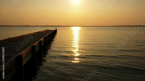 Sunset over calm sea dock.