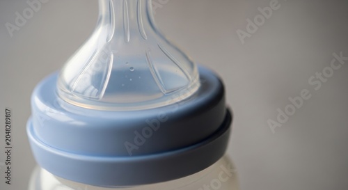 Close-up of a baby bottle nipple and cap with a soft focus background.