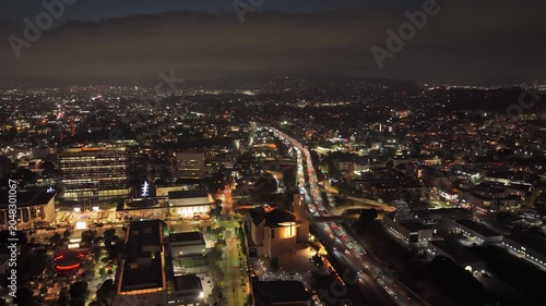 Urban metropolis of Los Angeles at night, with illuminated buildings and busy streets, Hollywood Freeway with heavy traffic under misty sky