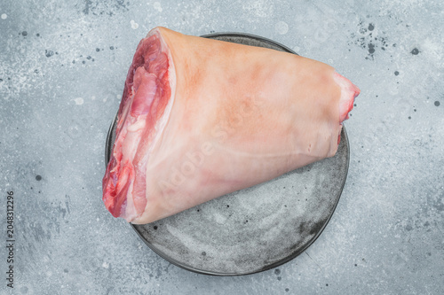 Fotografía Raw pork knuckle hock showing rind surface, subcutaneous fat and exposed muscle tissues on stone plate with thyme for technical culinary visuals