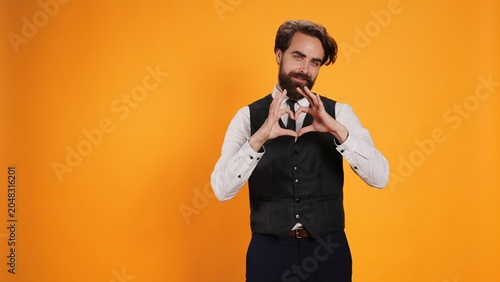 Obraz na płótnie Butler showing heart shaped symbol in studio, working at five star restaurant and uncovering sincere feelings