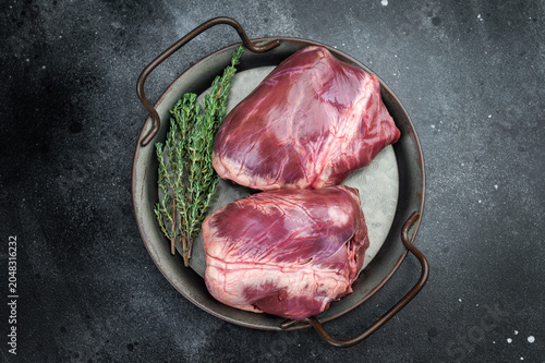 Картината върху платно Fresh veal hearts displaying dense myocardium and natural marbling arranged with herbs and spices on rustic dark surface