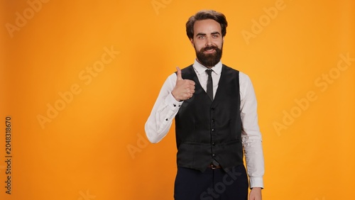 Bild auf Leinwand Trendy valet raises thumbs up gesture in studio to symbolize satisfaction and to indicate acceptance