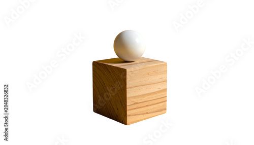A stark studio shot of a white sphere resting atop a textured, wooden cube, creating a simple geometric composition against a black background