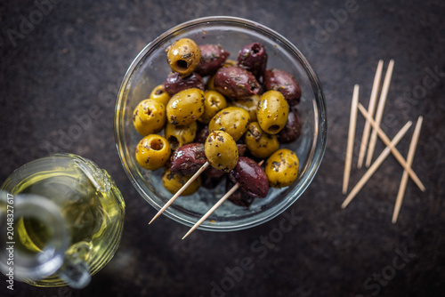 Marinated Green And Kalamata Olives In Glass Bowl With Olive Oil And Toothpicks