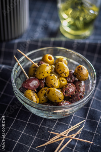 Marinated Green and Kalamata Olives in Glass Bowl With Toothpicks on Checked Cloth