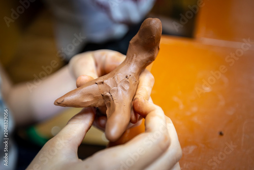 Fotografia A person's hands are engaged in shaping brown modeling clay, carefully forming an object during a creative activity