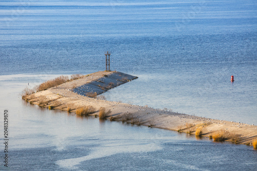 Canvas Print A concrete breakwater extends into a large body of open water, populated by nume