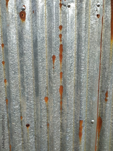 Weathered galvanized steel sheet with rust stains and corrugated texture, industrial metal background ideal for construction, architecture, and grunge design projects.