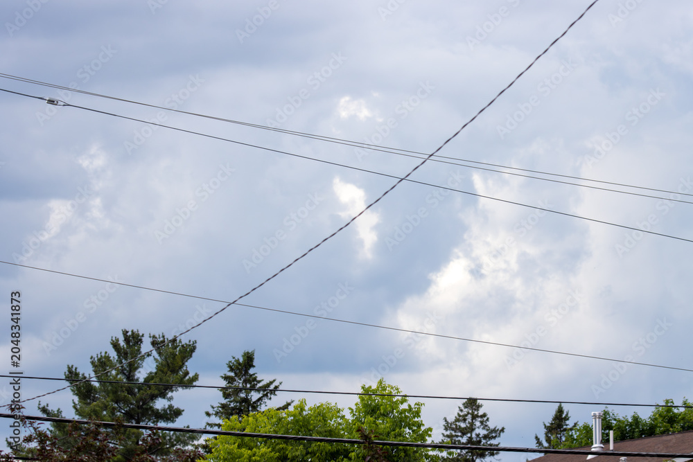 Fototapeta premium high voltage power lines with a cloudy sky and trees