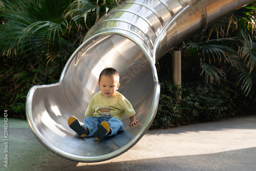 Asian child playing on playground slide