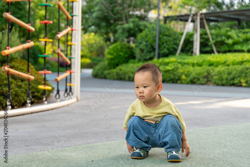 Toddler boy crouching in outdoor playground