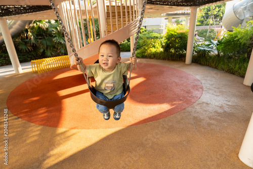 Asian child smiling on a swing at playground
