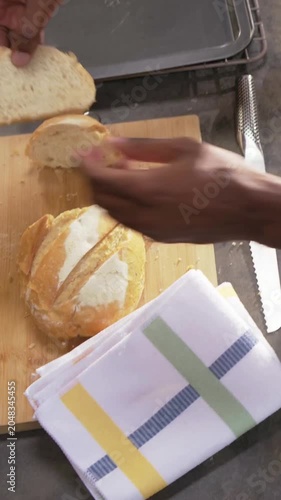 Vertical video: Holding serrated knife, cook's hands slicing round loaf in kitchen, checking crumb