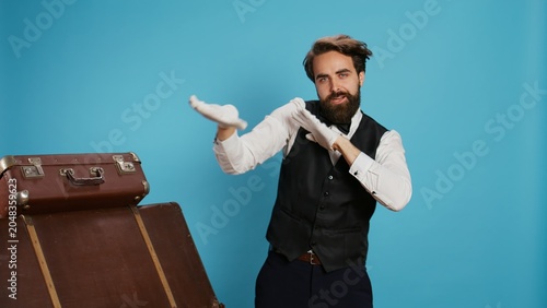 Foto Optimistic doorman dancing and having fun with modern groovy songs, stands against blue background
