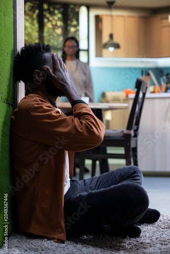 Schilderij op canvas Sad African American man sitting on the hallway floor and crying at home, Unhappy miserable person with depressive mood highlighting anxiety and mental illness, fatigue and frustration